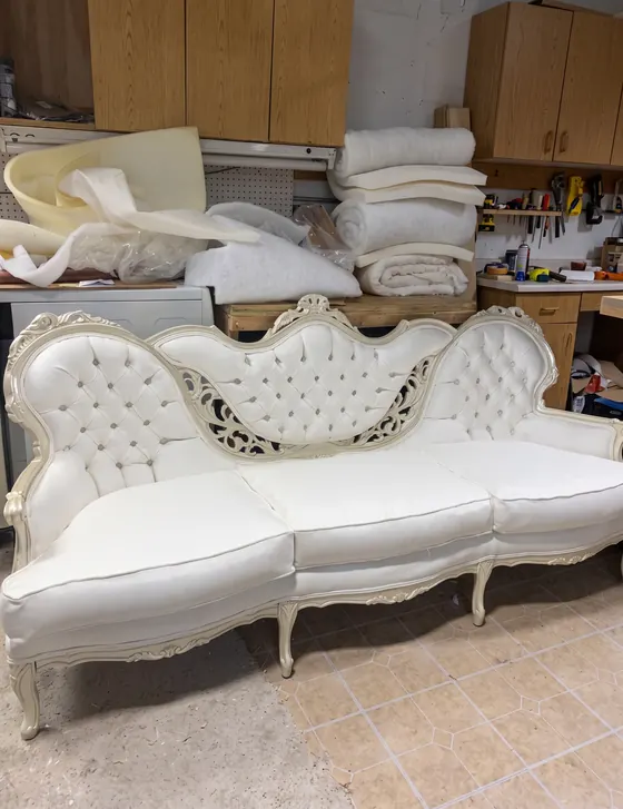 Sofá estilo francés con capitoneado blanco y madera tallada