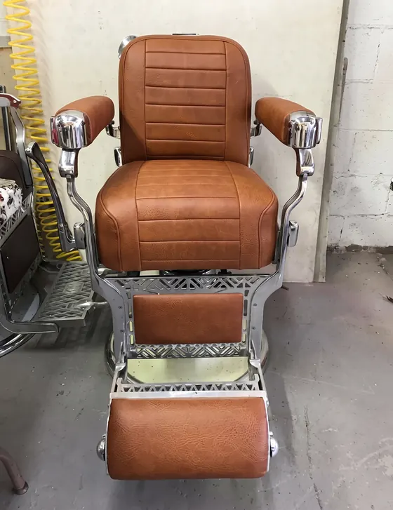 Silla de barbero antigua retapizada en piel café con costura horizontal