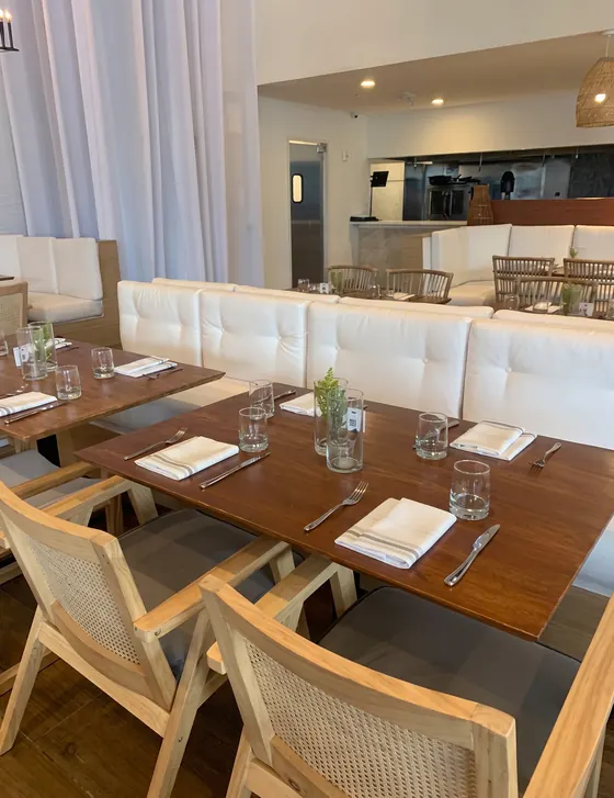 Banqueta de restaurante tapizada en blanco junto a mesas de madera