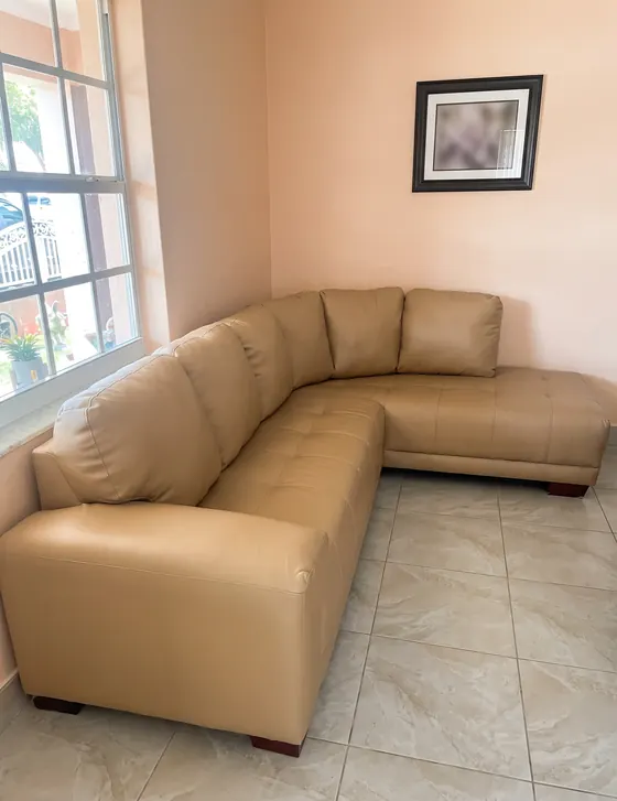 Sofá seccional en L retapizado en piel color arena en una sala
